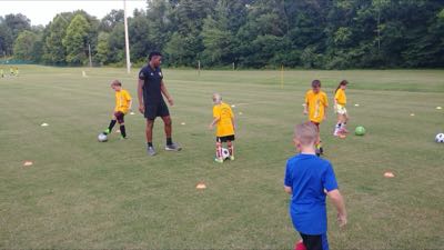 FC camper working a dribbling drill with a trainer